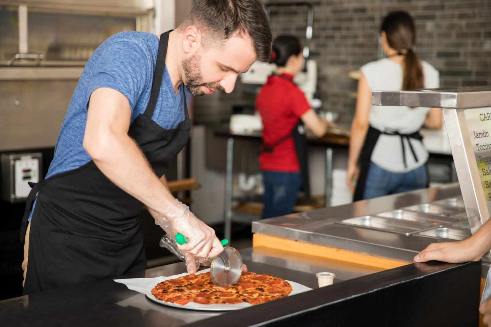Professional chef cutting pizza slices using a roller cutter